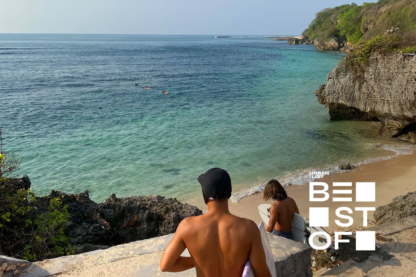 two people carrying surfboards walking down stairs to a beach